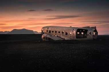 Gün batımına karşı dağdaki hasarlı uçak.