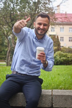 Avrupa 'nın bir şehrinde parkta oturan gömlekli bir adamın portresi. Ağaçların ve binaların arkasında bir adam. Stok fotoğrafları