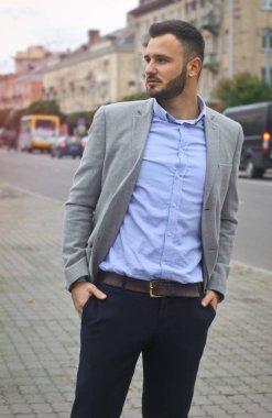 Bir Avrupa şehrinin yolunun yakınındaki sokakta bir iş adamının portresi. Sakallı yakışıklı bir adam şık giyinmiş. Modaya uygun bir hippi. Stok fotoğrafları