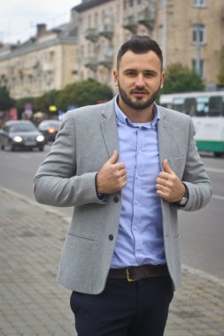 Bir Avrupa şehrinin yolunun yakınındaki sokakta bir iş adamının portresi. Sakallı yakışıklı bir adam şık giyinmiş. Modaya uygun bir hippi. Stok fotoğrafları