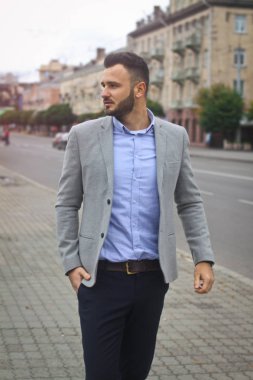 Bir Avrupa şehrinin yolunun yakınındaki sokakta bir iş adamının portresi. Sakallı yakışıklı bir adam şık giyinmiş. Modaya uygun bir hippi. Stok fotoğrafları