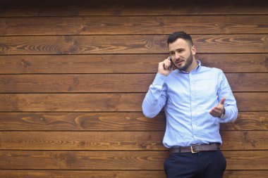 Ahşap bir arka planda gömlekli yakışıklı bir adamın portresi. İş adamı, şık giyinmiş patron. Telefonda konuşan seksi bir adam. Stok Fotoğraf Tasarımı