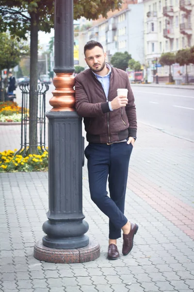 Mann in Jacke und Anzug auf einer europäischen Straße mit Kaffee in der Hand. Geschäftsmann modische Kleidung. Herbstlandschaft, Porträt. Archivbild — Stockfoto