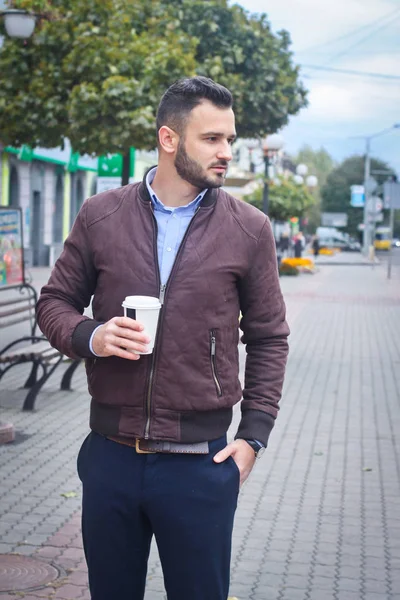 Человек в пиджаке и костюме на европейской улице с кофе в руках. Одежда бизнесмена. Осенний пейзаж, портрет. фото со склада — стоковое фото