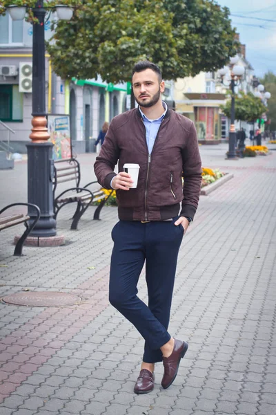 Mann in Jacke und Anzug auf einer europäischen Straße mit Kaffee in der Hand. Geschäftsmann modische Kleidung. Herbstlandschaft, Porträt. Archivbild — Stockfoto