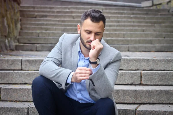 Portrait of a bearded man near the big steps of an old European castle. Businessman thinking over a future project. Fashionable guy with stylish clothes.