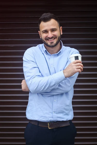 Retrato de um homem de negócios, gerente em um fundo de parede listrado. Homem barbudo sexy cantando café, chá. Fotografias — Fotografia de Stock