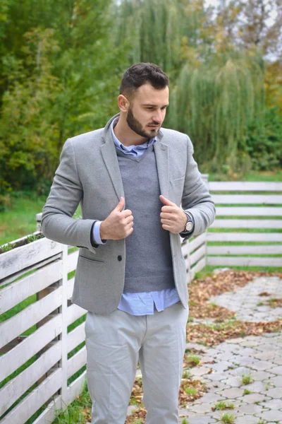 Portrait d'un homme sexy habillé en costume. Homme à la mode dans la nature d'automne près d'une clôture en bois blanc. L'homme d'affaires se détend. Skok photo pour la conception — Photo