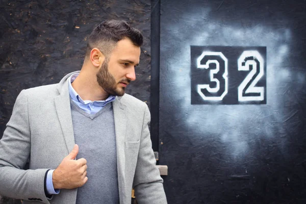 fashionably dressed man against the background of the graded wall. The guy and the old inscription 32. Creative photo for the design