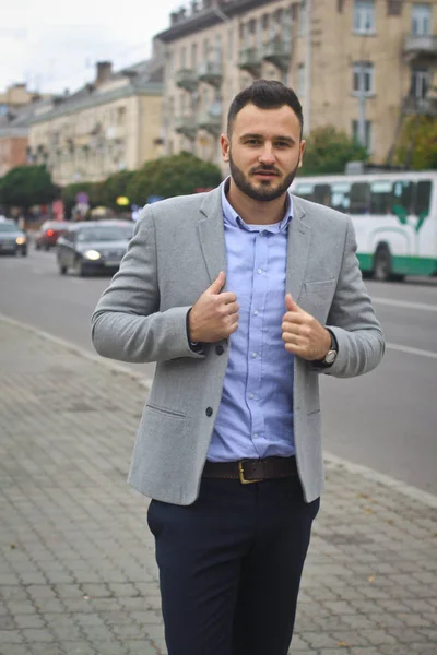 Portrait of a businessman on the street near the road of a European city. A bearded handsome man dressed stylishly. Fashionable guy hipster. Stock photos Stock Image