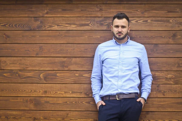 Portrait d'un bel homme en chemise sur un fond de mur en bois. Homme d'affaires, patron dans des vêtements élégants. Stock Photo pour le design Image En Vente