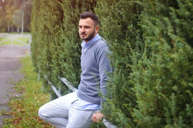 Avrupa, Amerikan şehrinin arka planındaki genç adam. Ağaçların, tarlaların ve çitlerin arkasında bir adam var. İş için güzel bir arazinin sahibi.