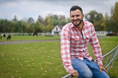 Genç yakışıklı Kovboy. Bir adam çitin yakınındaki çiftliğinde çiftçidir. Kırsal alanlar, kırsal alanlar. Ağaçlar, tarlalar, çiftlik. Stok fotoğrafları