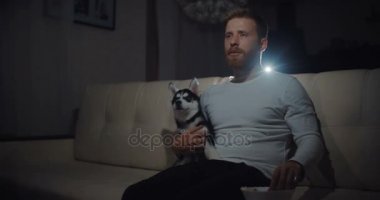 Genç drama evde oturma odasında Tv izlerken bir koltukta oturan köpekli adam ve ağlamaya başlar.