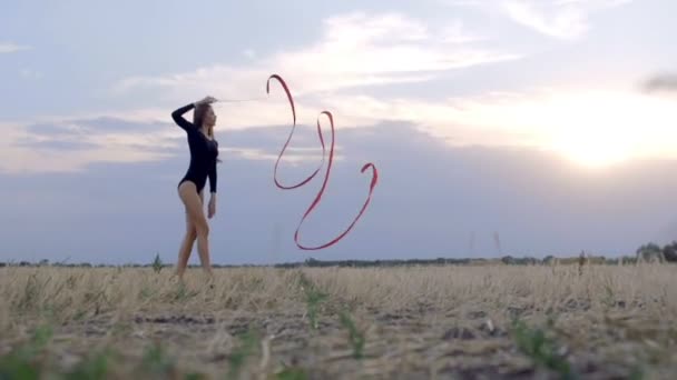 Mladá bruneta žena tanec moderní gymnastika, moderní s červenou stužkou. — Stock video