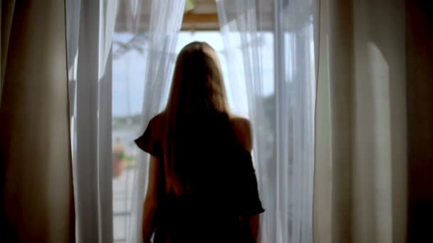 Una mujer va al exterior pasando por cortinas — Vídeos de Stock