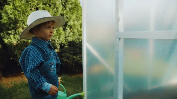 Kleine boer is invoeren van broeikas met gieter — Stockvideo