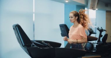 Spor salonunda treadmill çalıştıran çekici kıvırcık kız