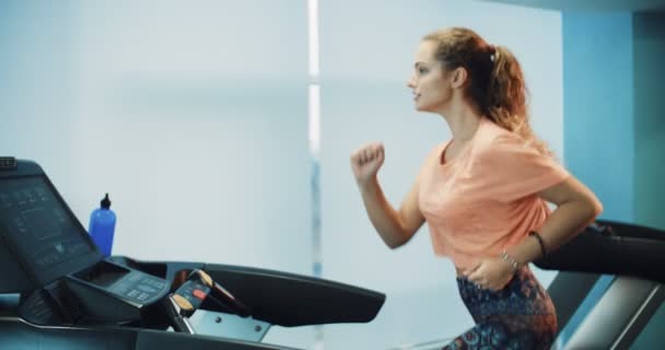 Attraktiva curly flicka kör på löpbandet i gymmet sport — Stockvideo