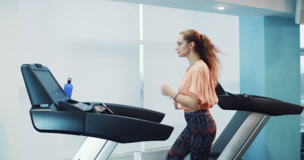 Chica atractiva corriendo en la cinta de correr en el gimnasio deportivo — Vídeos de Stock