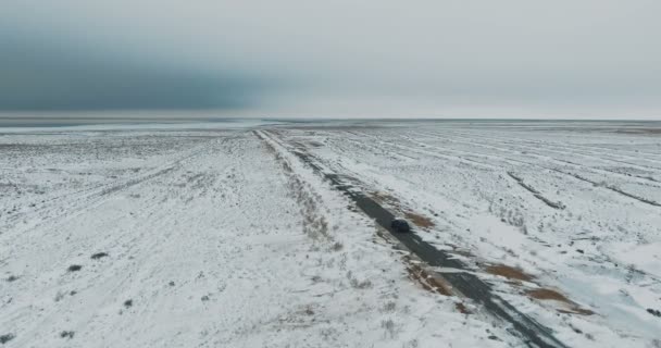 Zwarte auto rijden op winter landweg in het besneeuwde bos, luchtfoto van drone — Stockvideo