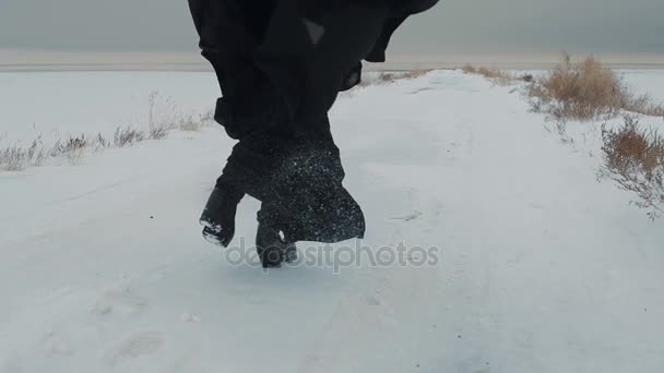 Belle jeune femme avec un mouchoir noir courant. Fond neigeux. Concept de mode hiver . — Video