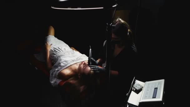 Professionelle Tätowierer arbeiten in dunklen schwarzen Raum. Schönheit weibliche Klientin. — Stockvideo