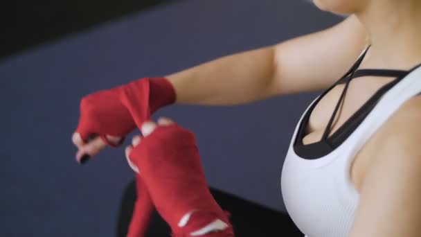 Vista de cerca de la joven mujer en forma hermosa polvo de polvo en sus manos envueltas en cintas de boxeo mientras se prepara para un entrenamiento en el gimnasio. Las mujeres envuelven sus manos con vendajes profesionales — Vídeos de Stock