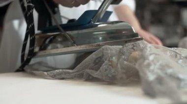 Uzman bir kadın terzi demir ile çalışır. Moda Tasarımcısı bir dantel elbise Ütü.