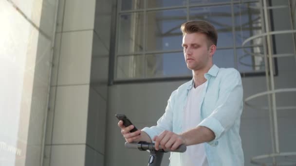 Een man met elektrische scooter met behulp van zijn telefoon buiten — Stockvideo