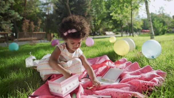 Küçük Afrikalı kız arka planda renkli balonlarla parkta oynuyor. — Stok video