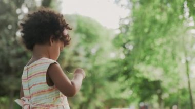 Küçük Afro-Amerikalı kız parkta büyüteçle oynuyor..
