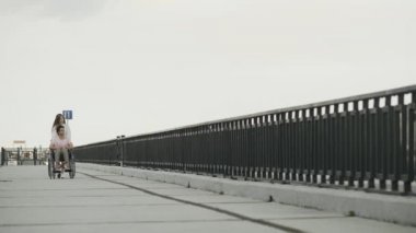 Tekerlekli sandalyedeki engelli adam ve kız arkadaşı setin üzerinde yürüyorlar.