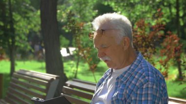 Yaşlı adamın yan görünüşü tablet bilgisayarın nasıl kullanılacağını anlamıyor
