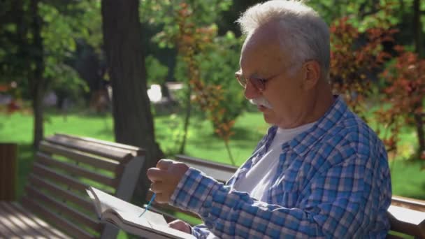 Anciano jubilado relajándose al aire libre leyendo un libro disfrutando de la jubilación — Vídeo de stock