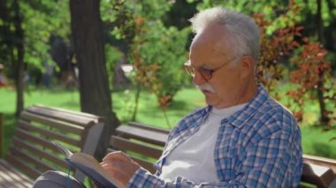 Kıdemli adam parkta tek başına kitap okuyor. Ve kendi kendine konuşuyor.
