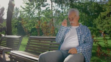 Parkta uyuyan bıyıklı yaşlı bir adam.