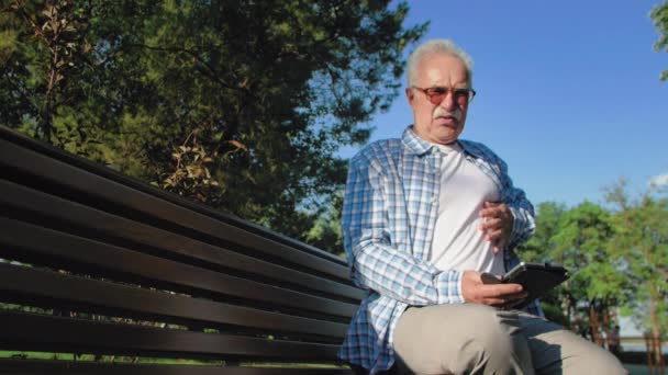 Un anciano estaba leyendo un libro y su corazón de repente le dolía — Vídeos de Stock