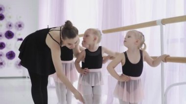 Bir grup küçük kız bale dersi sırasında yeni dans hareketleri öğreniyor.