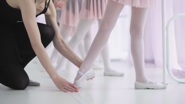 Närbild fötter oigenkännliga små flickor i vita strumpor och balett skor, deras balett lärare korrigera dem — Stockvideo