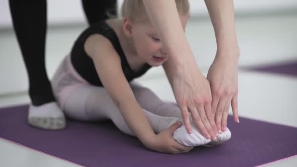 Klein meisje doen stretching oefeningen op studio vloer — Stockvideo