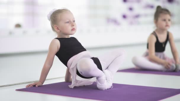 Маленькие девочки растягиваются и делают упражнения в балетной школе — стоковое видео