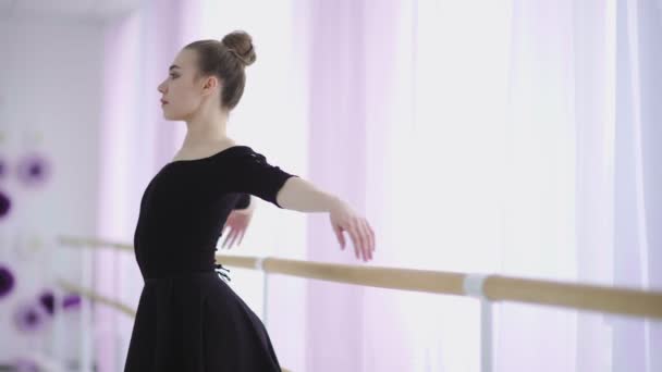 Ballerina warms up and stretches on barre in ballet gym — Stock Video