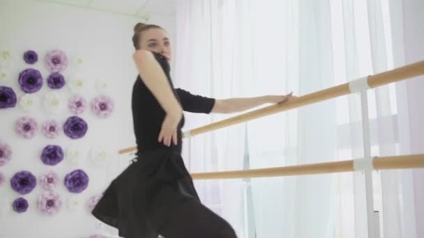 Geautiful ballerina dressed in black tutu dancing near a big window. — Stock Video