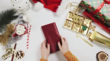 Noel hediyelerini paketlemek için kırmızı kağıt hazırlayan kadın