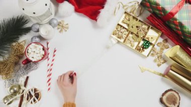 Noel hediyelerini paketlemek için kurdele kesen bir kadın.