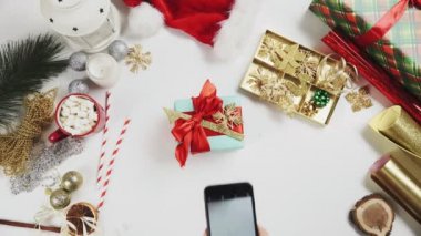 Üst düzey kadın Noel hediyesini beyaz masada fotoğraflıyor.