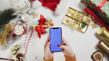 Üst görünüm elleri cep telefonu dokunmatik ekranı kullanıyor. Yılbaşı masasında çoklu dokunmatik jest anahtarı.