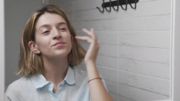 Fiatal nő alkalmazása krém és tükörbe nézve élvezze a természetes szépség és az egészséges — Stock videók