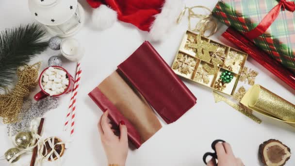 Femme coupant du papier rouge pour envelopper les cadeaux de Noël — Video